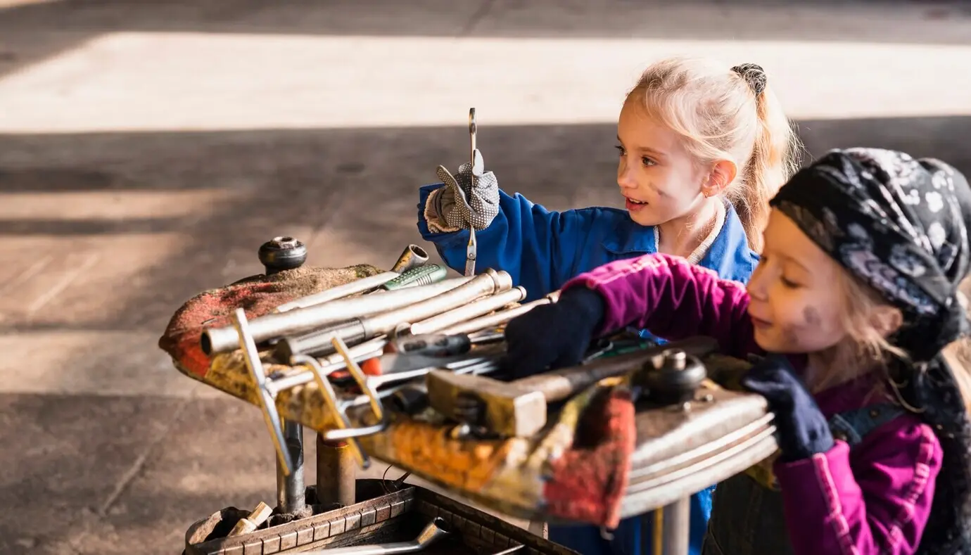Dos chicas adorables con overoles eligiendo herramientas.